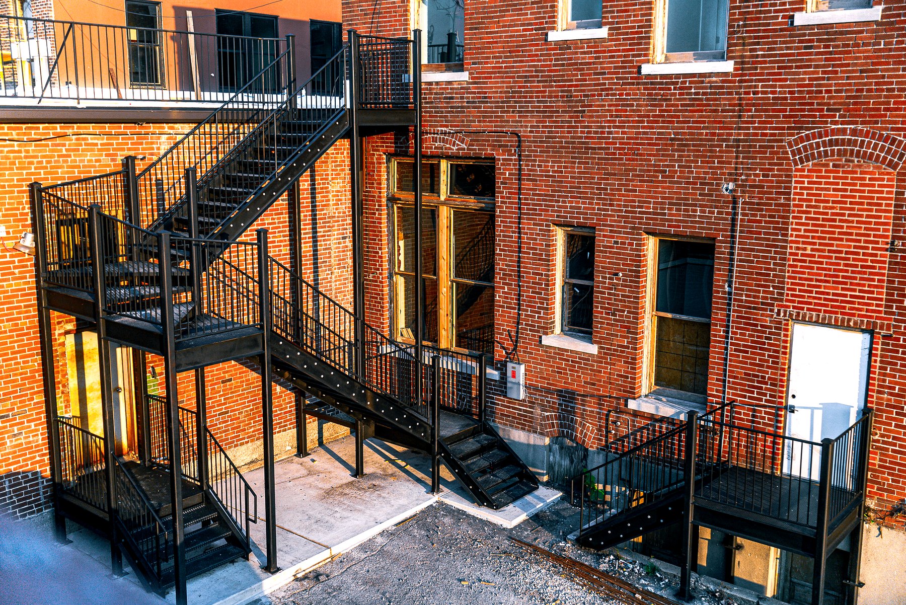 Black steel stairs and platform installed on the exterior of a brick building