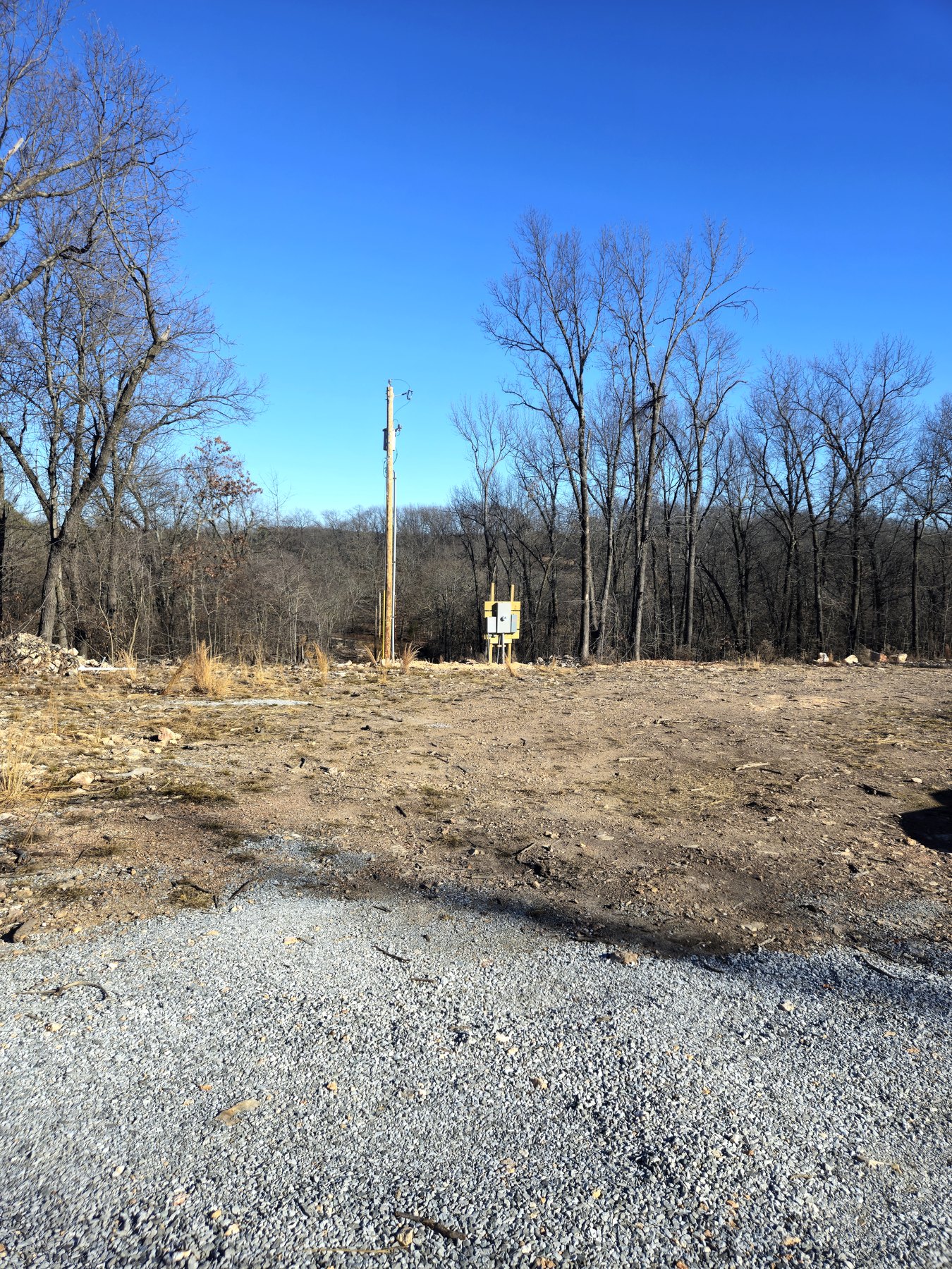 Cleared site with gravel drive and rough grading before construction