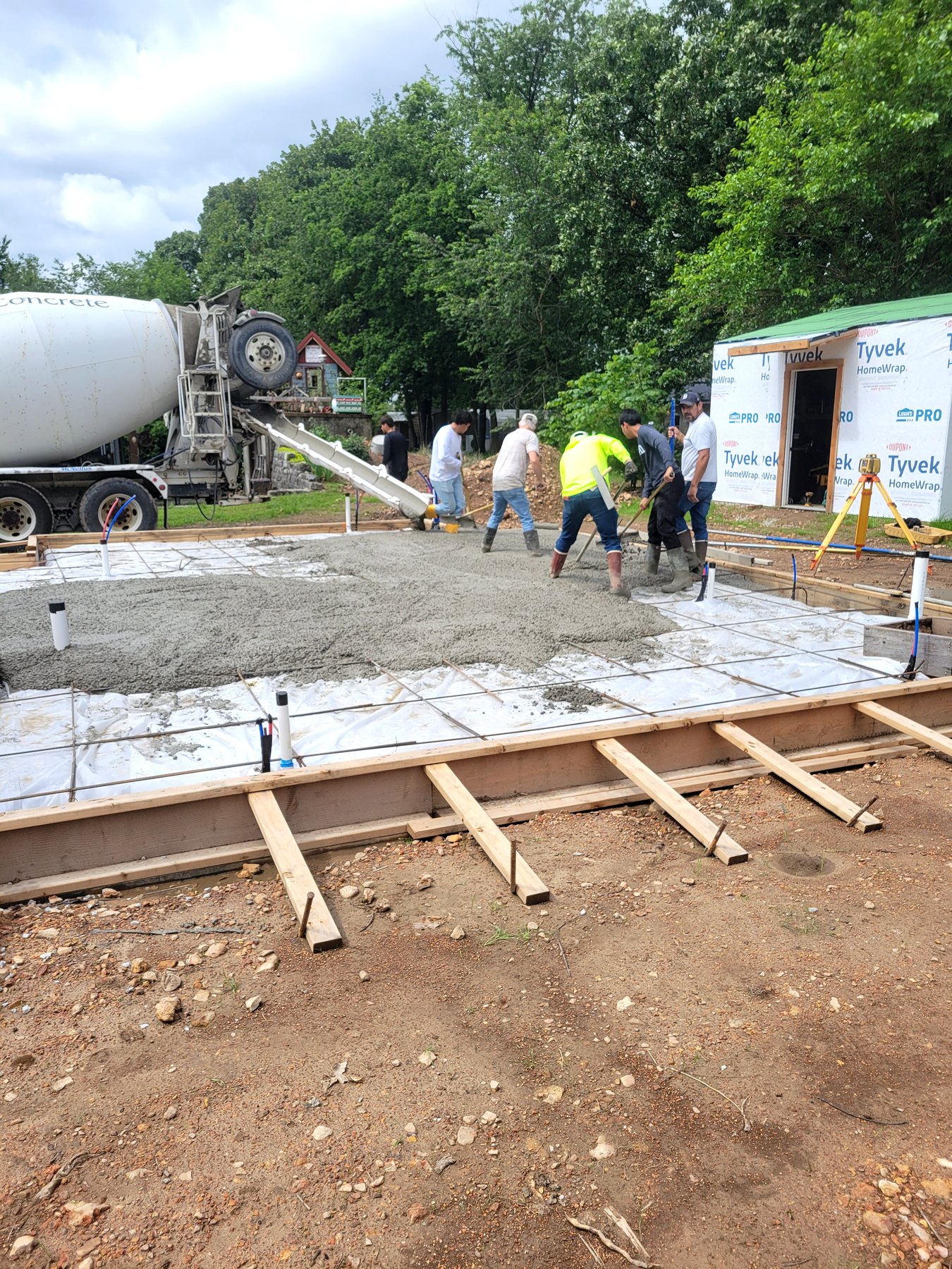 Crew working a concrete slab placement with forms and truck access nearby