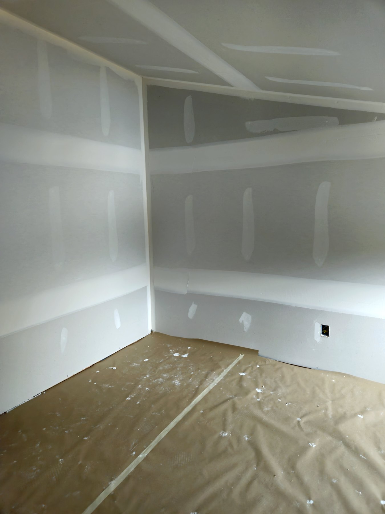 Drywall finish work with protective floor covering in an interior room