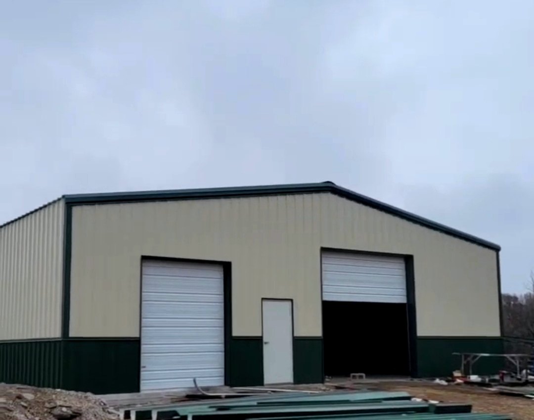 Completed commercial metal building with overhead doors and green wainscot