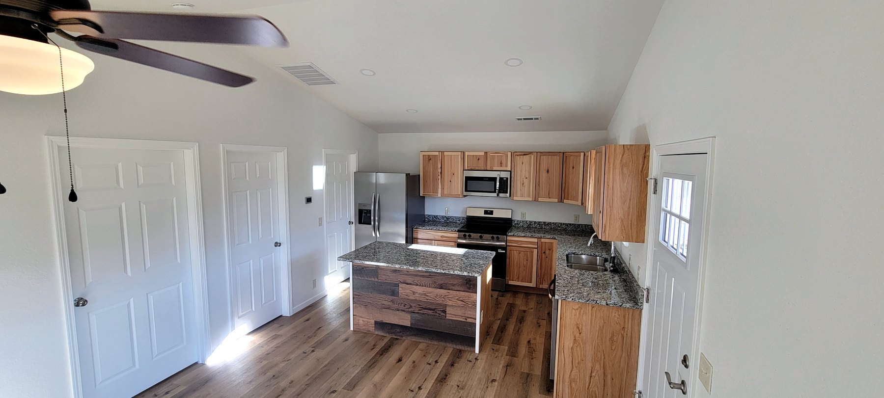 Finished residential kitchen and living space with wood cabinets and plank flooring