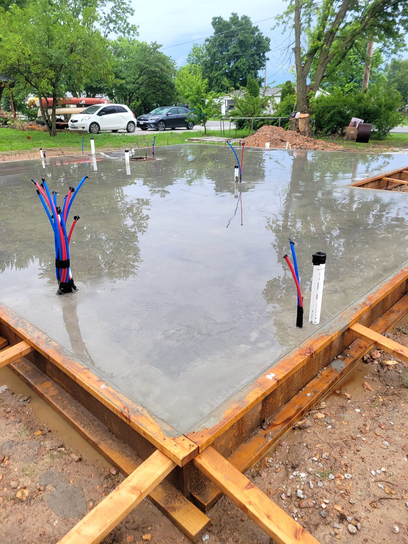 Fresh concrete slab being poured and finished with formwork and utility stubs in place