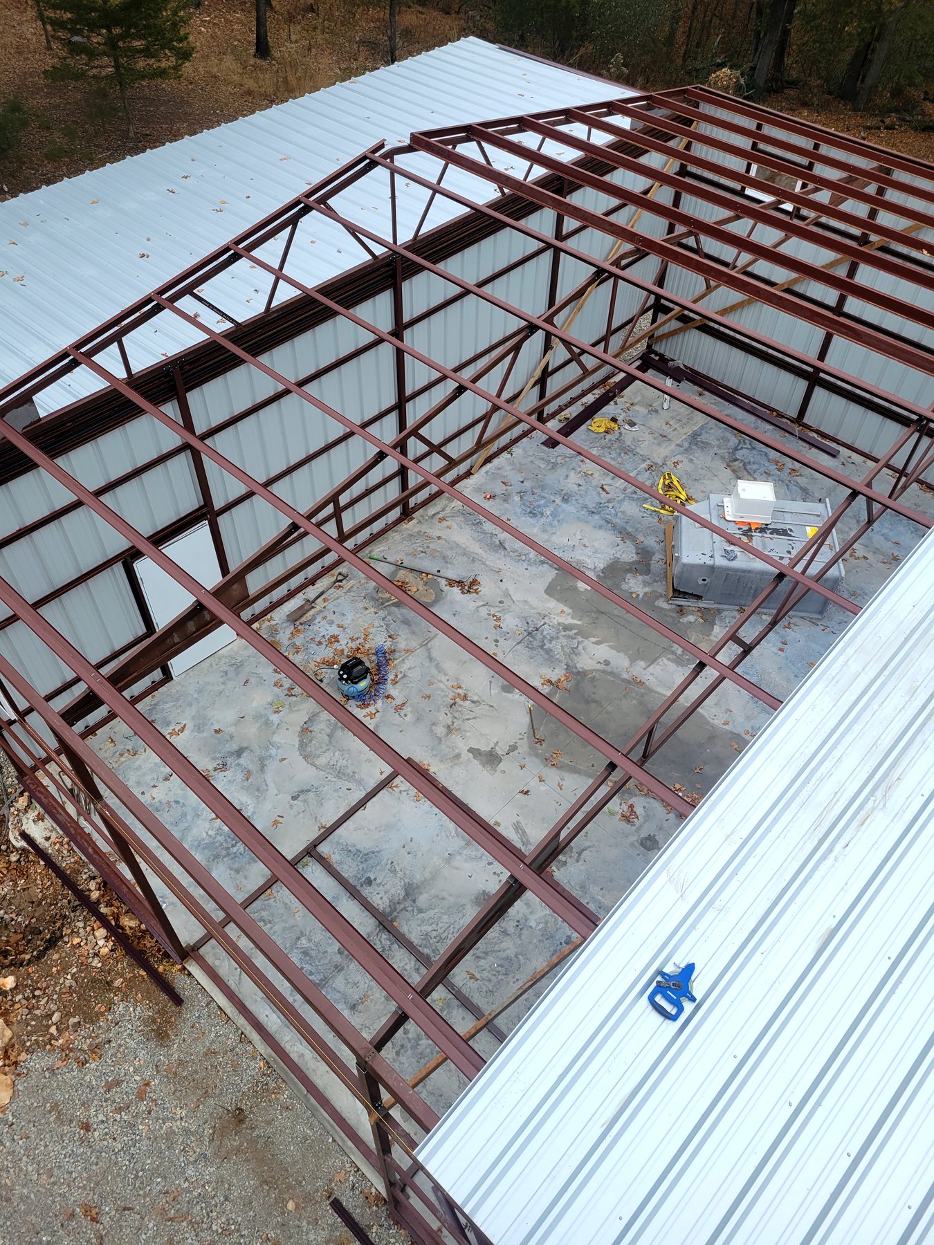 Metal roof panels being installed over a red iron building frame